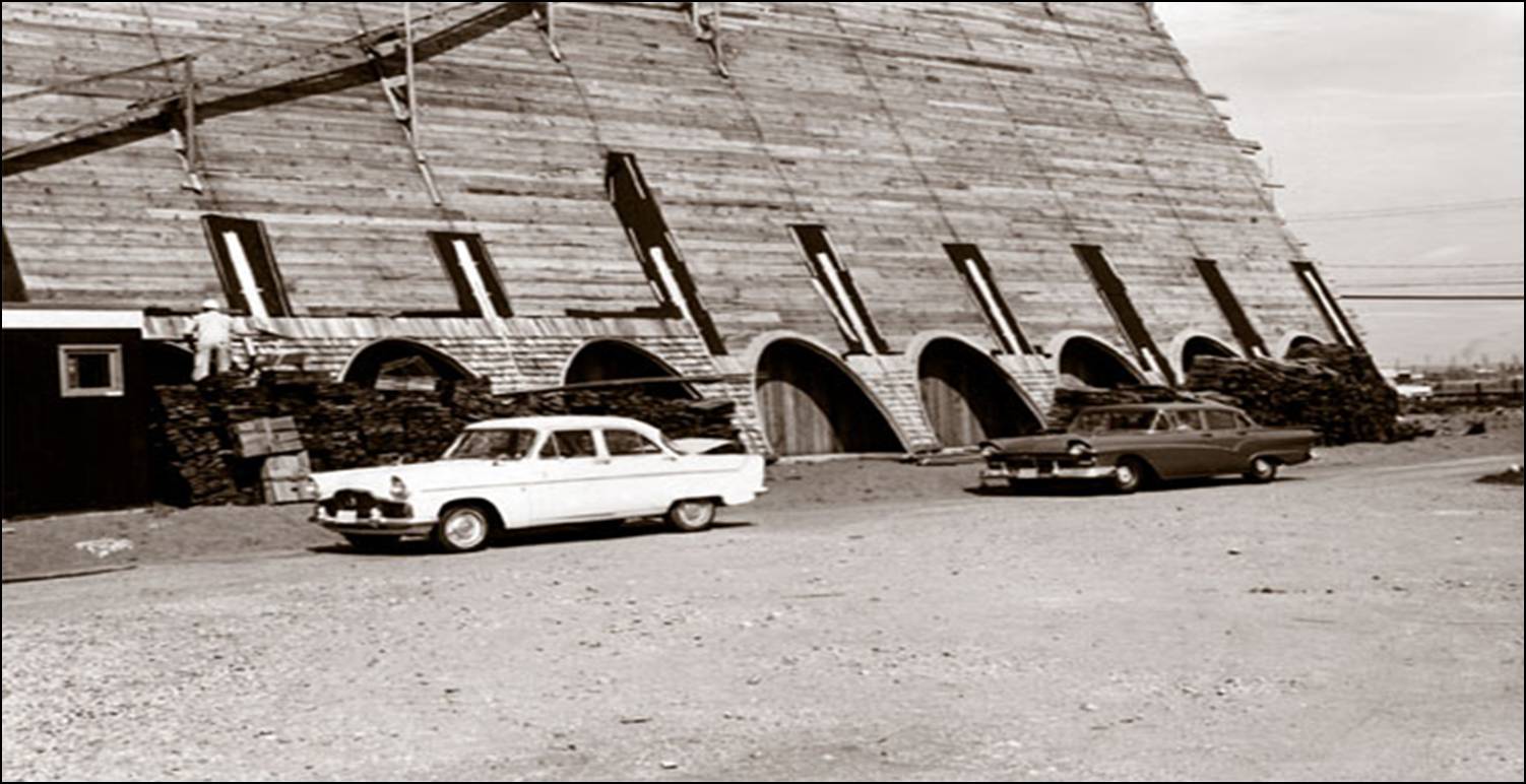 1964  historic photograph of the exterior of Trinity Lutheran Church during the final roofing stage in Richmond, BC. Workers are installing shingles over the steep A-frame roof, which features a series of distinctive archways along the base.