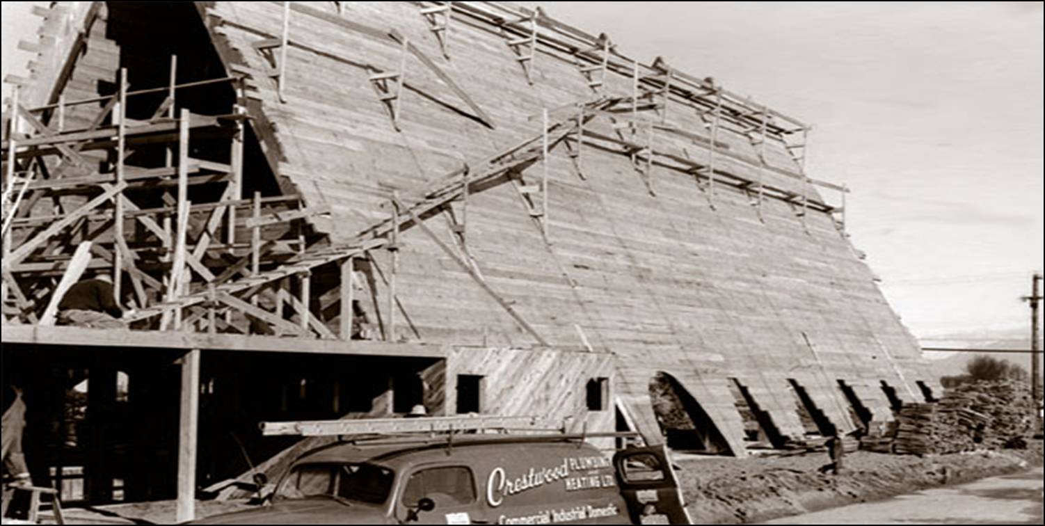 1964  historic construction of Trinity Lutheran Church in Richmond, showing the framing of the southern entrance and office wing. In the background, scaffolding is in place to finish the roof and gable of the large A-frame structure, while a Crestwood Plumbing and Heating service truck is visible in the foreground